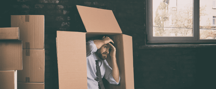 Man anxious hiding in a carton box